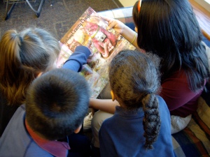 Middle school student reading "Anamalia" to 1st graders.